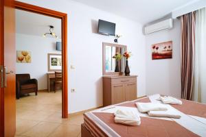 - une chambre avec un lit, un miroir et une chaise dans l'établissement Antigone Hotel, à Thasos