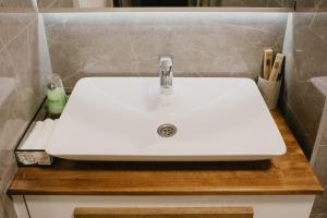 a white sink on a wooden counter in a bathroom at Akro Studio apartman in Tuzla +17 photos