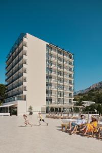 a group of people on a beach with a building at Bluesun hotel Neptun - All inclusive in Tučepi