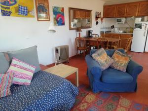 a living room with a blue couch and a kitchen at Cozy Country House near Beaches in Azoia