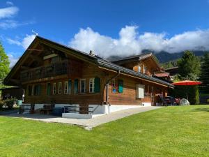 una grande casa in legno con un prato verde di fronte di Chalet Herrschaft a Grindelwald
