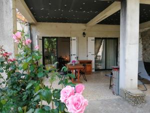 eine Veranda mit rosa Rosen und einem Holztisch in der Unterkunft La Dolce Vita Studio indépendant avec terrasse in Vals-les-Bains