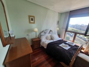1 dormitorio con 1 cama con tocador y ventana en Acacias - Piso amplio en Playa de Poniente para 6personas con garaje, en Gijón