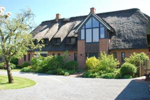 a large house with a thatched roof at Ferienwohnung unter Reet in Westerhever