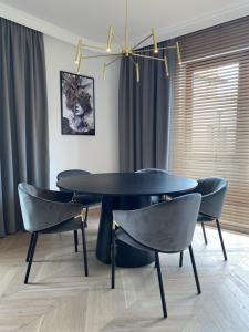 a dining room with a black table and chairs at Apartament Baltica z Tarasem - tuż przy plaży - dwupoziomowy in Rogowo