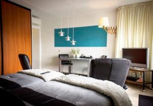 a bedroom with a bed and a desk and a television at Studio PolderPoort in Kampen