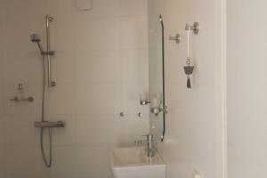 een witte badkamer met een wastafel en een douche bij Studio PolderPoort in Kampen