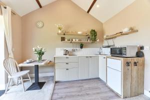 a kitchen with white cabinets and a table with a microwave at Host & Stay - The Pepper Pot in Alnwick
