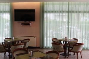 a dining room with tables and chairs and a flat screen tv at Hotel Palme in Lido di Jesolo