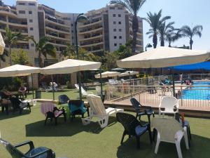 a group of chairs and umbrellas next to a pool at A Dream Place in Raanana, up to 5 guests - Swimming Pool - Jacuzzi & Gym in Ra‘ananna