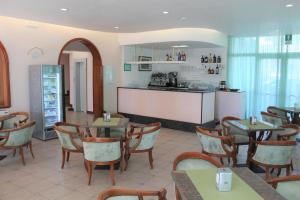 a restaurant with tables and chairs and a kitchen at Hotel Palme in Lido di Jesolo