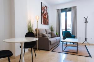 ein Wohnzimmer mit einem Sofa, einem Tisch und Stühlen in der Unterkunft Guardamino Dúplex Suite Apartment in Sevilla