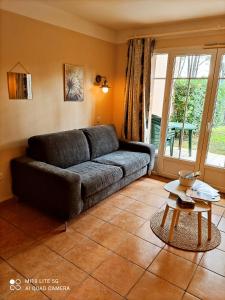 a living room with a couch and a table at Maisonnette mitoyenne 2 étoiles paisible piscine océan lac vélo marche idéal pour tous in Lacanau-Océan