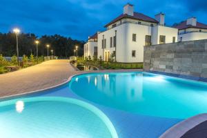 a swimming pool in front of a building at night at Apartament Baltica z Tarasem - tuż przy plaży - dwupoziomowy in Rogowo