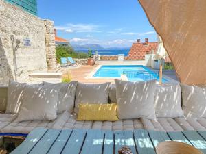 a couch with pillows sitting next to a swimming pool at Eco Sunshine Apartments Lumbarda in Lumbarda
