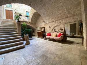 a living room with a couch and a stone wall at Palazzo Morola XIV century in Giovinazzo
