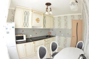 een keuken met witte kasten en een tafel met stoelen bij Apartamenty na NIzhney Dubrove 19 in Vladimir