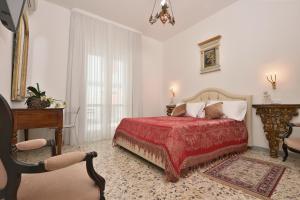 a bedroom with a bed with a red blanket and a chair at Casa Real in Minori