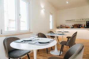 une salle à manger avec deux tables et des chaises blanches dans l'établissement Centoquindici Rooms & Suite, à Montesilvano