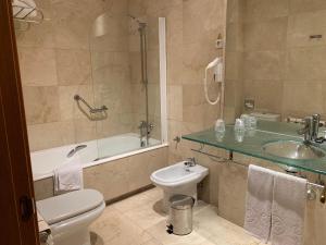 
a bathroom with a toilet, sink, and bathtub at Exe Gran Hotel Almenar in Las Rozas de Madrid
