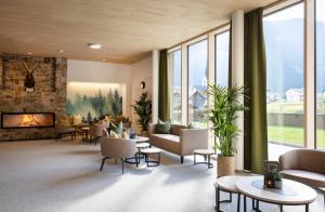 eine Lobby mit Sofas und Stühlen sowie einem Kamin in der Unterkunft JUFA Hotel Savognin in Savognin