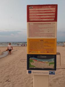 a sign on the beach with people walking on the beach at Отдельная комната в Юрмале in Jūrmala