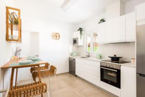 a kitchen with white cabinets and a table and a stove at Villa Menorca ROCAS by Mauter Villas in Cala en Bosc