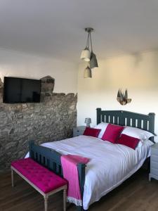 a bedroom with a bed and a tv on a stone wall at Raymond House B&B Penally, Tenby in Penally