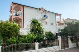 a large white house with a fence in front of it at Apartments Majić in Hvar