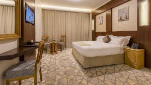 メディナにあるJiwar Al Madina Hotelのベッドとデスクが備わるホテルルームです。