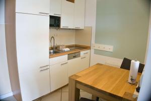 a kitchen with white cabinets and a wooden table at FeWo mit Garten-, gratis Nutzung vom AHOI Erlebnisbad und Sauna in Sellin - Haus Blick zur See FeWo 12 in Göhren