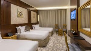 a hotel room with two beds and a flat screen tv at Jiwar Al Madina Hotel in Al Madinah