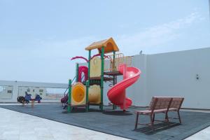 a playground with a slide and two chairs at Sand Beach Suites(Families only) in Rayyis