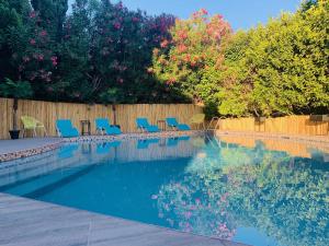 a swimming pool with blue chairs and a fence at Grand Hôtel de Nîmes 4 étoiles in Nîmes