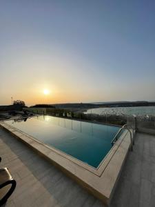 a large swimming pool with the sunset in the background at Hotel VIU57 in Mellieħa