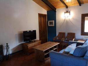a living room with a couch and a tv at La Casa Blanca del Alto Tajo in Ablanque