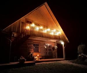 una casa de madera con luces en el techo por la noche en Zaķu muiža, en Anspoki