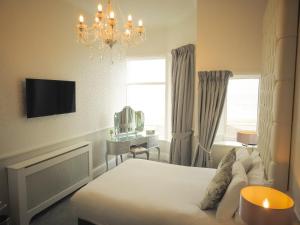 a bedroom with a bed and a desk and a chandelier at Park House Hotel in Blackpool