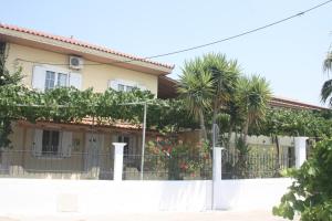 a house with palm trees and a fence at MARIA STUDIOS LAGANAS in Laganas