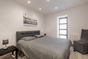 ein Schlafzimmer mit einem großen Bett und einem Stuhl in der Unterkunft Appartement en front de mer avec terrasse et vue mer in Arromanches-les-Bains