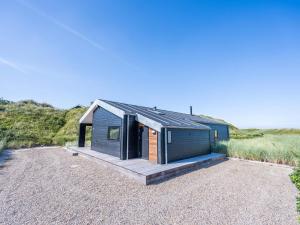 een klein huis met een houten veranda en een terras bij 6 person holiday home in Henne in Henne Strand