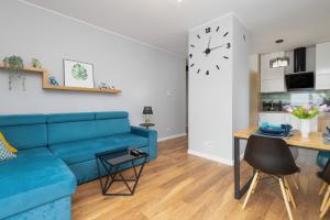 a living room with a blue couch and a table at Albatross Towers Przymorze Apartments by Renters in Gdańsk