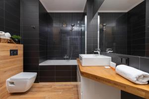a bathroom with a sink and a toilet and a tub at Albatross Towers Przymorze Apartments by Noclegi Renters in Gdańsk