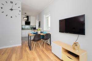 a living room with a table and a clock on a wall at Albatross Towers Przymorze Apartments by Renters in Gdańsk