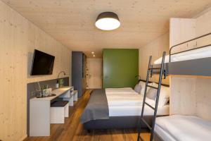 1 Schlafzimmer mit 2 Etagenbetten und einem TV in der Unterkunft JUFA Hotel Savognin in Savognin