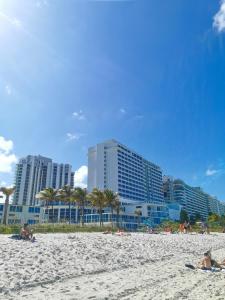 a group of people laying on a beach with buildings at New Point Miami Beach Apartments in Miami Beach