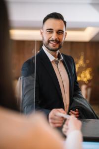 un hombre de traje sentado en una mesa en Hotel Jelena, en Banja Luka