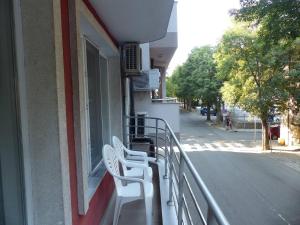 uma varanda com cadeiras brancas do lado de um edifício em Apartament HOLIDAY em Burgas