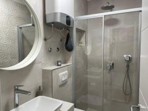 uma casa de banho com um chuveiro, um lavatório e um espelho. em Apartment in city center 2 em Split