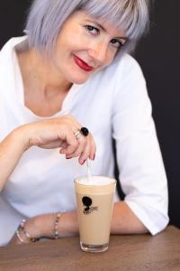 Eine Frau, die an einem Tisch mit einer Tasse Kaffee sitzt. in der Unterkunft Motel Schlafraum Schlüßlberg-Dein smartes Hotel-contactless check-in in Schlüßlberg